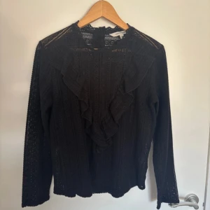 Svart spetsblus  - Säljer en svart spetsblus från KappAhl med volangdetaljer framtill.