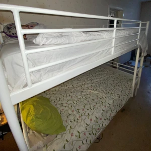Vit våningssäng i metall  - Säljer en praktisk vit våningssäng i metall med två sängplatser. Den övre sängen har säkerhetsräcke och stege för enkel åtkomst. Perfekt för barnrummet eller gästrummet. Madrasser ingår ej.