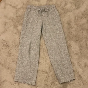 Grå mjukisbyxor med dragsko - Säljer ett par grå mjukisbyxor med dragsko i midjan. Byxorna har en avslappnad passform och är tillverkade i ett mjukt material. Perfekta för en bekväm dag hemma eller en avslappnad utflykt.