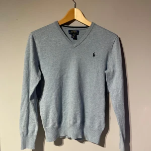 Blå v-ringad tröja från Ralph Lauren - Säljer en stilren blå v-ringad tröja från Ralph Lauren. Tröjan är använd 1 gång och har inga skavanker. Skriv gärna om ni undrar något om tröjan.