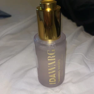 Ida Warg Tanning Drops - Säljer Ida Warg Tanning Drops i en stilren flaska med guldlock. Perfekt för att ge huden en solkysst look. Enkel att använda och blanda med din vanliga hudvård. Oanvänd