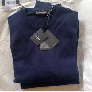 Gran Sasso 100% Kashmir tröja  - Säljer en elegant mörkblå tröja i 100% kashmir från Gran Sasso. Tröjan har en klassisk design med rund hals och är perfekt för att hålla dig varm och stilren. Tillverkad i Italien, vilket garanterar hög kvalitet och komfort. Storlek 48 = M/S. Nypris 3999kr. Helt ny med alla tags som från butik. 