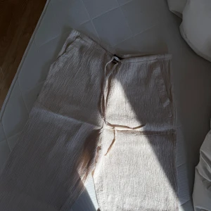 Beige byxor från ZARA - Säljer ett par bekväma beige byxor från ZARA. De har en avslappnad passform med dragsko i midjan för justerbarhet. Perfekta för en ledig stil.
