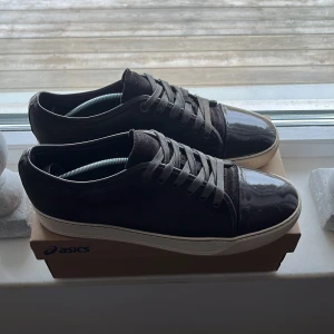 Lanvin skor  - Snygga lanvins med glansig finish och klassisk snörning. Skorna har en vit sula som ger en stilren kontrast. Perfekta för en avslappnad och trendig look.