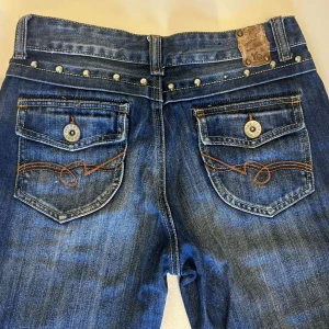 Blå jeans med nitar - Snygga blå jeans med dekorativa nitar vid fickorna och bak. De har en klassisk femficksdesign och en cool tvättad look. Perfekta för en avslappnad stil med en touch av edge. Pris diskuterbart vid snabb affär💕💕
