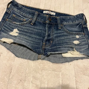 Blå jeansshorts från Hollister - Snygga blå jeanskjol från Hollister och de är perfekta nu till sommaren. De har en låg midja och är i storlek W24.