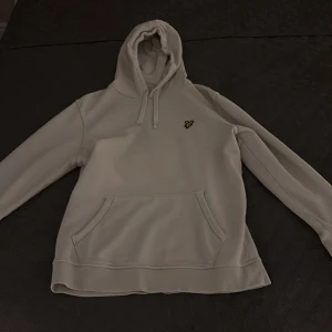 Grå hoodie från Lyle & Scott - Säljer en stilren vit hoodie från Lyle & Scott i ekologiskt material. Den har en klassisk design med en liten logotyp på bröstet. Typ aldrig använd .