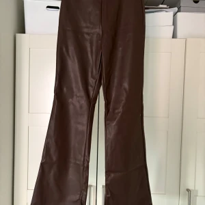 Bruna skinnbyxor från H&M - Snygga bruna skinnbyxor från H&M med en stilren design. Byxorna är bootcut, midi i midjan och är perfekta för en trendig look. De är tillverkade i ett skinnliknande material som ger en cool och modern känsla. Likadana som de svarta