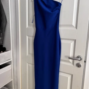 Blå långklänning med oneshoulder - Elegant blå långklänning med en stilren oneshoulder-design. Klänningen har en smickrande passform och en diskret dragkedja i ryggen. Perfekt för en speciell kväll!