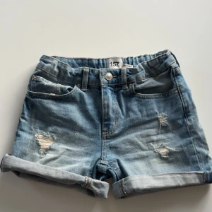 Blå jeansshorts - Snygga blå jeansshorts från Lager 157 i modellen Sunny star, med slitna detaljer och uppvikta ben. De har en bekväm passform och är inte för stela i materialet. Dom är i storlek 150 men passar för mig som vanligtvis bär xs