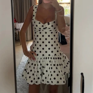 Vit kort prickig klänning med volang - Supersöt vit kort klänning med svarta prickar och volangig kjol. Helt slutsåld online!!!! 💓💓 lappen är kvar och endast testad