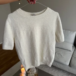 Vit stickad kortärmad tröja H&M - Supermjuk vit stickad tröja från H&M med korta ärmar och rund halsringning. Tröjan har en enkel och clean look med ribbade muddar vid hals, ärmslut och nederkant. 💛