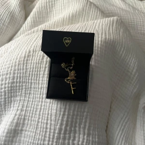 Guldhalsband från Maria Nilsdotter - Snyggt och stilrent halsband i guld från Maria Nilsdotter med en tunn kedja och en berlock formad som bokstaven F. 