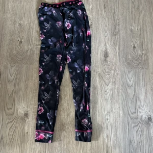 Blommiga svarta leggings från Everest - Snygga svarta leggings från Everest med blommigt mönster i rosa och lila toner. Resår i midjan med logga och rosa detaljer vid benslut. Perfekta för träning eller chill dagar.