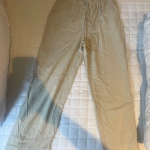 Beiga linnebyxor med snörning - Snygga och avslappnade beiga linnebyxor med dragsko i midjan. Perfekta för varma dagar och chill vibes. Lätta och luftiga med en loose passform och elastisk midja för extra komfort. Pris går att diskutera! 