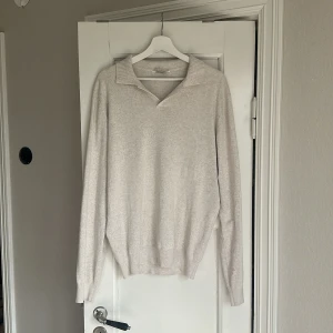 Beige stickad polotröja med krage - Snygg beige stickad polotröja med klassisk krage och v-ringad öppning. Köpt på John Henric för 899kr. 