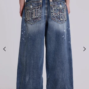 Rock Revival x Jaded London wide jeans - Säljer ett par blåa wide jeans från Rock Revival x Jaded London. De har stora broderade bakfickor med coola detaljer, kontrastsömmar och stänk-effekter på benen. Jeansen har låg midja och är tillverkade i klassiskt denimtyg. Skriv gärna för fler bilder eller frågor!💕