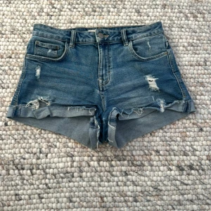 Blå jeansshorts med slitningar Zara - Hej!! Säljer dessa jättefina shorts från Zara i storlek 36 med midjemåttet 36 cm. Jag har de lite nere på höfterna för en avslappnad och baggy look. Tveka inte på att skriva vid frågor🤗