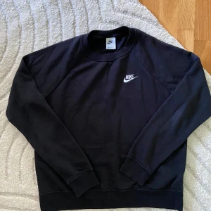 Svart Nike sweatshirt i bomull M - Helt ny och oanvänd, så nyskick! Svart sweatshirt från Nike i storlek M. Klassisk crewneck med broderad vit Nike-logga på bröstet. Tillverkad i mjuk bomullsmix, perfekt för en chill och sportig look. Långärmad modell med ribbade muddar och avslut.