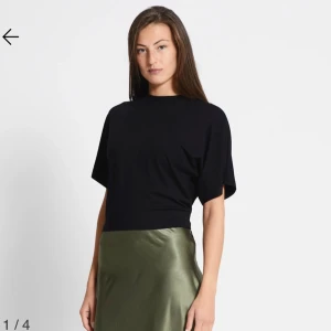 Svart croppad t-shirt - En stilren svart t-shirt med croppad passform och korta ärmar. T-shirten har en klassisk rund halsringning och är tillverkad i mjuk bomull som känns skön mot huden. Perfekt att matcha med kjol eller jeans för en clean look.