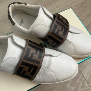 Vita Fendi sneakers med logoband - Säljer mina Fendi sneakers då de ej kommer till användning. De är knappt använda och är i superfint skick! Köpta för 4000kr säljer för 3000kr. Går att diskuteras vid snabb affär!