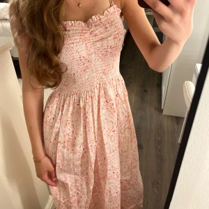 Blommig sommarklänning  - Supersöt blommig klänning från H&M i ljusrosa och vita toner med smock upptill och tunna axelband. Nytt skick då jag aldrig har använt den!💗