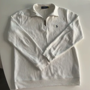 Vit Ralph Lauren half-zip - Stilren och klassisk vit half-zip tröja från Ralph Lauren. ✅ Äkta vara ✅ Storlek: S ✅ I princip oanvänd – i nyskick ✅ Nypris: 1100 kr 💸 Nu endast 450 kr!  Perfekt både till vardags och för en mer uppklädd look. Säljer endast p.g.a. garderobsrensning. Passa på att fynda en kvalitetsklassiker till ett riktigt bra pris!