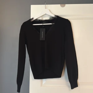 Svart blus med spets från Trendyol - Supersnygg svart tröja från Trendyol med v-ringning och fina spetsdetaljer vid halsen. Långärmad modell i mjukt material som sitter skönt.