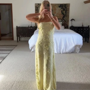 Ljusgul axelbandslös långklänning - Säljer denna superfina ljusgula långklänning med axelbandslös design och blommigt mönster. Klänningen har en rak passform. Den är i storlek 32 och endast testad på en gång, prislapp kvar!🩷Klänningen är helt slutsåld på hemsidan.