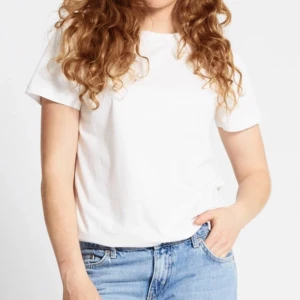 Vit basic t-shirt  - Enkel och stilren vit t-shirt med rund hals och korta ärmar. Modellen är rak och har en normal passform, perfekt till jeans eller shorts. Tillverkad i mjuk bomull som känns skön mot huden.