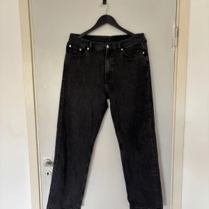 Svarta wide jeans från Weekday - Säljer ett par svarta jeans från Weekday i modellen Galaxy. Jeansen har en rak och wide passform med klassiska fem fickor och hög midja. Materialet är robust denim i bomull och färgen är tvättad svart för en cool look.