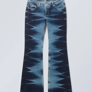 Low waist Bootcut jeans  från Weekday - Säljer ett par unika bootcut jeans från Weekday i blått med coolt grafiskt mönster längs benen. Jeansen har klassisk femficksdesign, low waist  och är tillverkade i jeansmaterial. Knappt använda, 1-2 gånger.