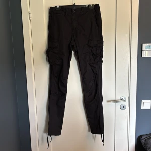 Svarta cargobyxor Jack & Jones - Svarta cargobyxor från Jack & Jones med loose fit. Byxorna har flera stora fickor på sidorna och snörning vid bensluten. Tillverkade i bomull, perfekta för en avslappnad och streetig stil.