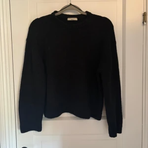 Svart stickad tröja från Gina Tricot - En svart, klassisk stickad tröja från Gina Tricot storlek S. Jätte användbart plagg. Tröjan är en ullblandning med 14% ull och 7%allpacka. Tröjan är i ett bra skick men har ett litet hål (bild 4) på vänster arm. Det är dock enkelt att laga själv.