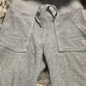 Grå mjukisbyxor Juicy Couture XS - !!Kan köpas som ett par med matchande juicy kofta, få 400 rabatt genom att köpa dem tillsammans!! Grå mjukisbyxor från Juicy Couture med broderad logga på fickan och breda fickor framtill. Byxorna har dragsko i midjan med silvriga detaljer och är tillverkade i mjukt bomullsmaterial. 