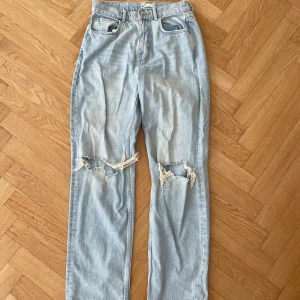 Ljusblå jeans - Ljusblå jeans med raka ben och slitna hål över knäna från Gina. Storlek 38