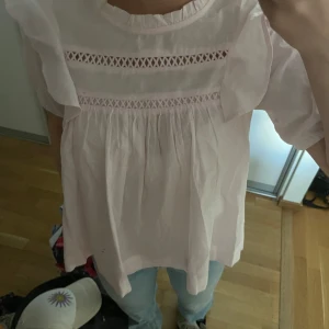 Ljusrosa blus med volangärmar - Supersöt ljusrosa blus med volangärmar och två dekorativa spetsband över bröstet. Blusen har en lös passform och är tillverkad i ett tunt, luftigt bomullstyg. Storlek 170 o passar mig som använder xs/s!🥰