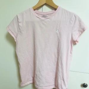 Ljusrosa t-shirt från Polo Ralph Lauren - Snygg ljusrosa t-shirt från Polo Ralph Lauren med klassisk passform och diskret broderad logga på bröstet. Tillverkad i 100% bomull för en mjuk och skön känsla. Lite defekter som man ser på bilden men inget som syns när man har den på sig. Köpt av mig på ralph laurens egna hemsida.❤️