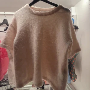 Beige stickad tröja med kort ärm - Supermjuk och fluffig beige stickad tröja med korta ärmar och rund hals. Tröjan har en avslappnad passform och är perfekt för lager-på-lager. Passar dig som gillar en enkel men cozy stil.