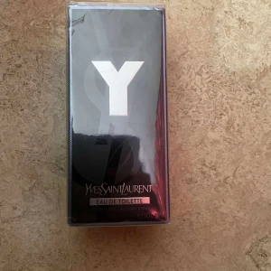 Yves Saint Laurent Y Eau de Toilette 100ml - Y Eau de Toilette från Yves Saint Laurent i en snygg svart och silverfärgad kartong med stor vit Y-logga. Flaskan rymmer 100 ml och är en klassisk herrdoft. Förpackningen är av kartong och plast, med stilren och modern design.