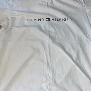 Tommy Hilfiger T-Shirt - Vit Tommy hilfiger t shirt i storlek xs. Själv aldrig använt men den är begagnad, osäker om den ens är använd då inga tecken på användning. Tar emot bud
