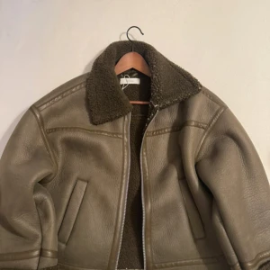 Brun-grön teddyjacka med dragkedja - Säljer en brun-grön teddyjacka från Reserved med mjukt foder och bred krage i teddy.  Jackan är i bra skick men har vita prickar på insidan som lätt går att ta bort.💕