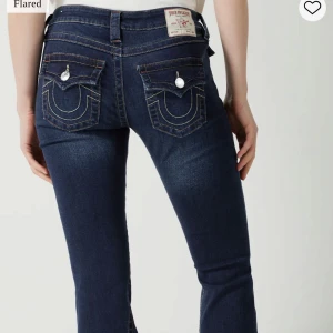 True Religion joey bootcut jeans - Mörkblå bootcut jeans från True Religion. Snygga fickdetaljer bak med lock och silverfärgade knappar. Jeansen är lågmidjade och även uppsydda snyggt så dom passar en som är mellan 160-167 perfekt i längden. Skriv för egna privata bilder eller funderingar💗 Bara använda nått fåtal gånger så väldigt fint skick!