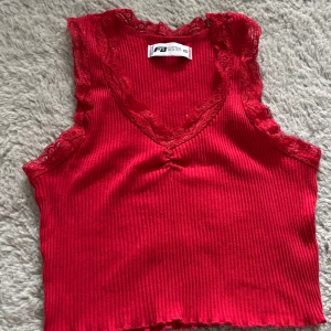 Röd ribbad linnetopp med spets - Snygg röd ribbad linnetopp från FB Sister i storlek XS. Toppen har v-ringning och ärmlös design med fina spetsdetaljer längs halsringning och ärmhål. 