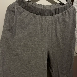 Grå mjukisbyxor från H&M Divided - Gråa mjukisbyxor från H&M Divided med resår i midjan och muddar vid bensluten. Tillverkade i en mjuk bomulls- och polyestermix. Perfekta för chill dagar eller när du vill vara extra bekväm.