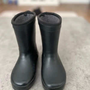 Svarta fodrade stövlar - Svarta stövlar med rund tå och platt sula. De är tillverkade i syntetmaterial och har ett mjukt foder på insidan som gör dem extra sköna när det är kallt och blött ute. Perfekta för regniga dagar och höstväder.