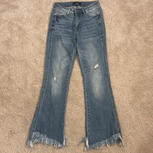 Blå bootcut jeans Viva Couture - Snygga blå bootcut jeans från Viva Couture i klassisk denim med slitna detaljer på benen. Jeansen fickor, dragkedja och knapp framtill. Perfekta för dig som gillar en avslappnad och trendig look.