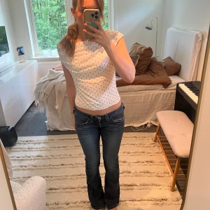 True Religion bootcut jeans låg midja - Säljer ett par vintage blå jeans från True Religion med låg midja och bootcut. Snygga detaljer och ikoniska bakfickor med lock och knappar. Jeansen har en lätt tvättad look och är i mjukt denimtyg.