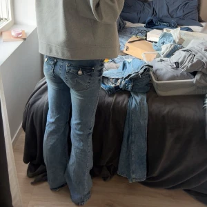 Blå bootcut jeans med detaljer - ett par snygga populära Nelly  jeans med låg midja och coola fickdetaljer bak med knappar och broderi. Jeansen  har använts fåtal gånger och har slitning på ena hälen ( inget som syntes på, fråga om bild) 😊 priset är diskuterbart