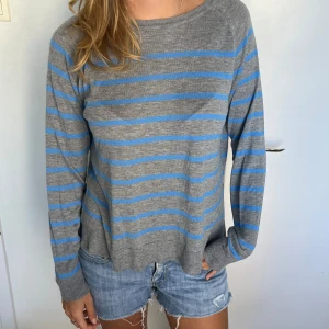 Gråblå randig tröja från Zara - Säljer en chill grå tröja från Zara med blåa ränder. Tröjan är långärmad och har en avslappnad passform, perfekt till jeans eller shorts. Mjuk och tunn i materialet, superenkel att styla för en casual look.